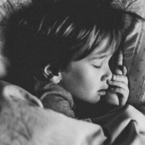 grayscale photo of girl sleeping on white pillow